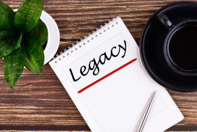 Legacy text, inscription, phrase is written in a notebook that lies on a wooden table and a pen. Business concept.