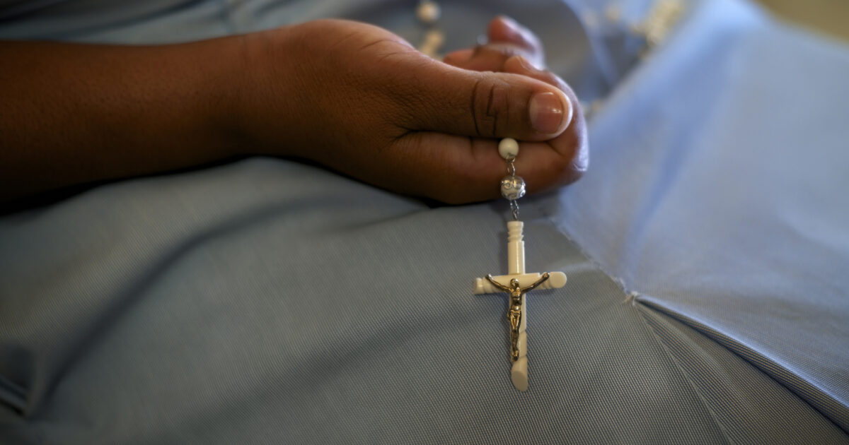 People and religion, catholic sister praying in church and holding cross in hands. With model release