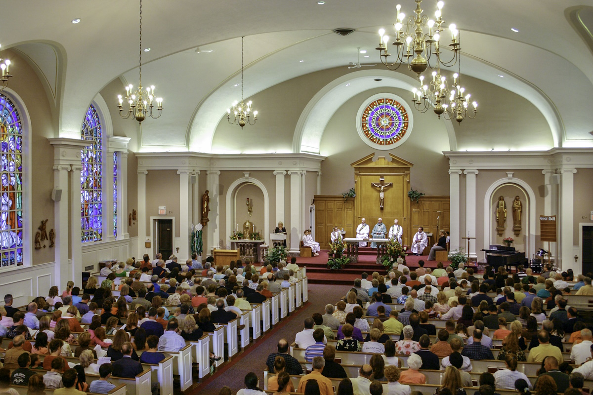 A large crowd gathered for a celebration of Catholic Mass in a bright church.