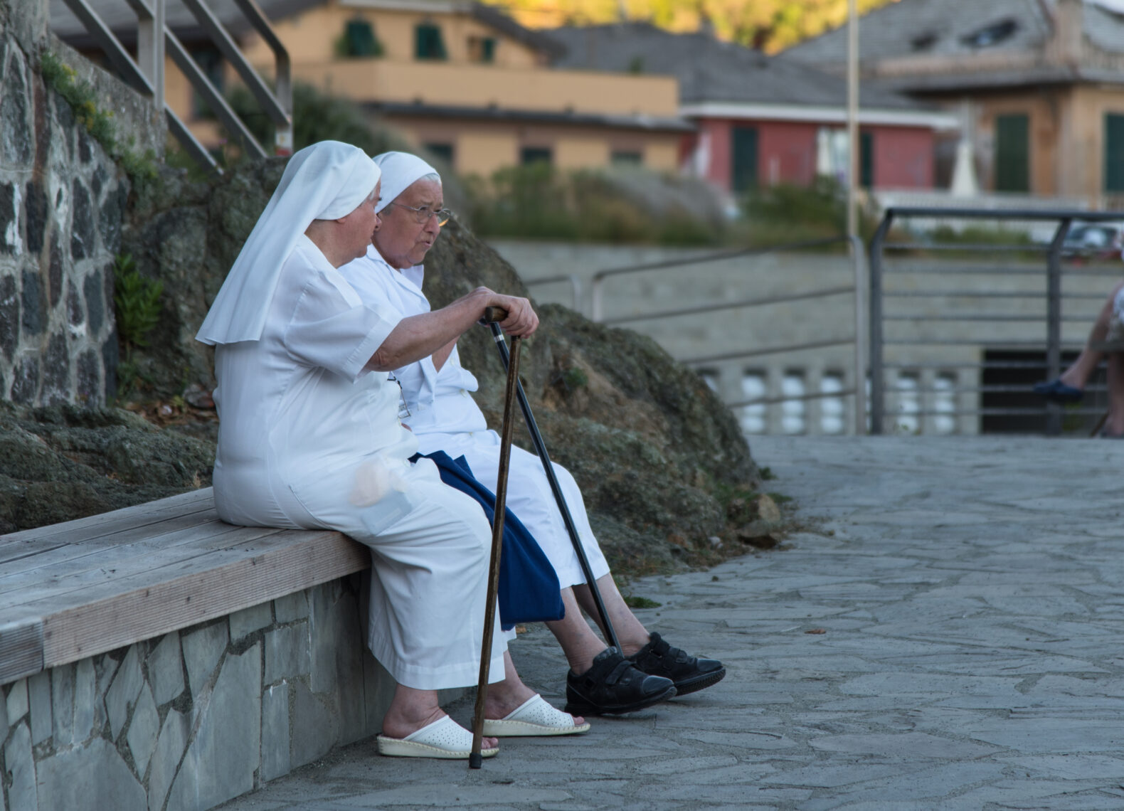 Bonassola, Liguria / Italy - August 24, 2016: two nuns sitting on a bench on the promenade by the sea, resting and enjoying the conversation in the early evening