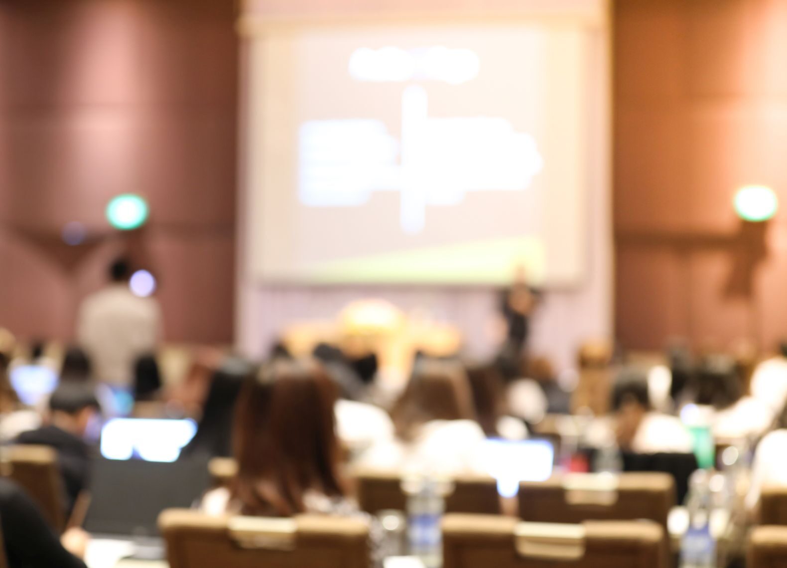 Abstract blurry background of employees seminar and De-focus teamwork staffs working meeting in conference room with projector screen.