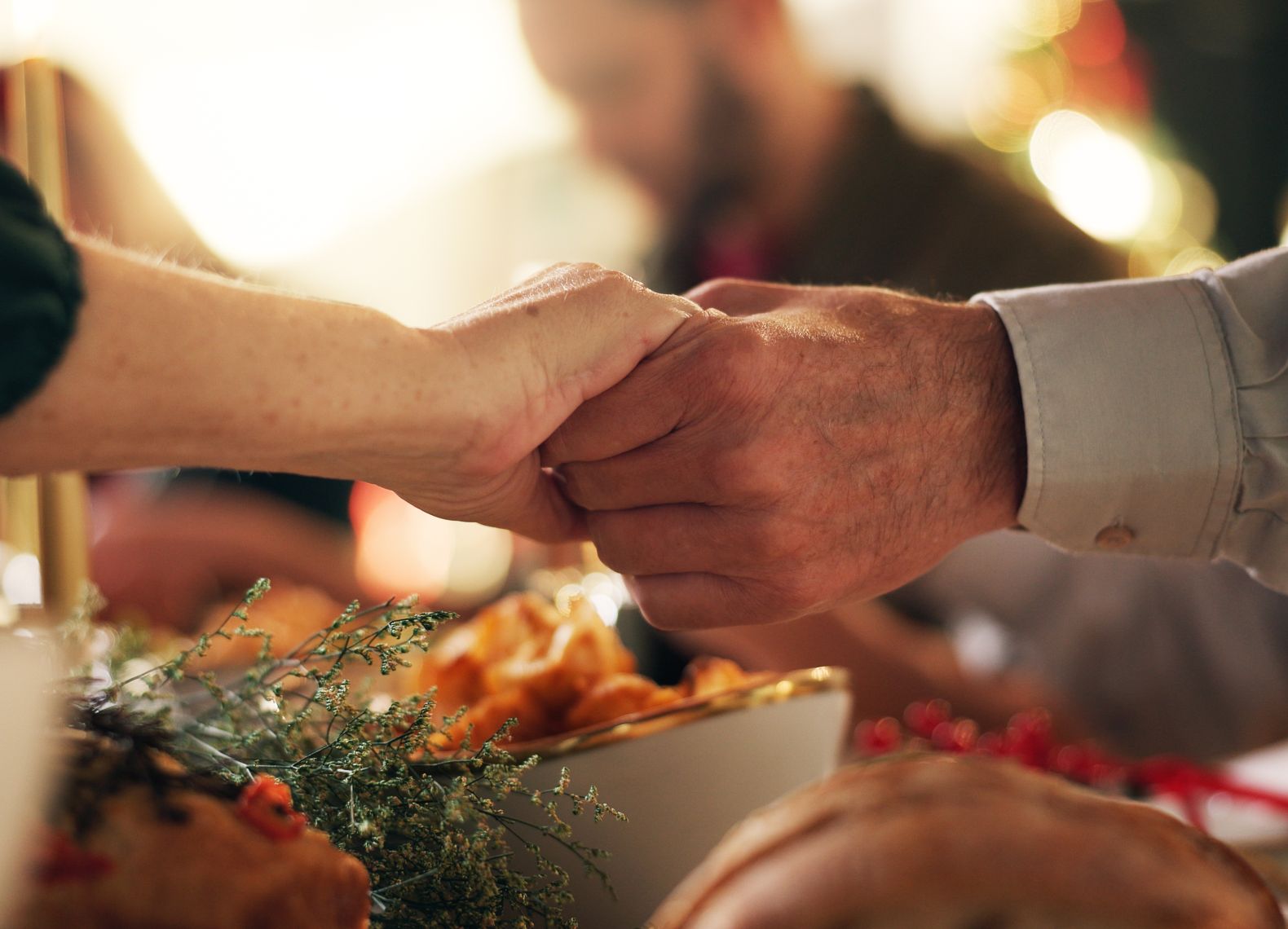 Holding hands, Christmas and prayer with family at dinner table for gratitude, holiday season and love. Worship, spiritual and support with closeup of people in home for festive celebration and trust