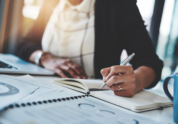 Cropped shot of a businesswoman making notes at her desk in a modern office