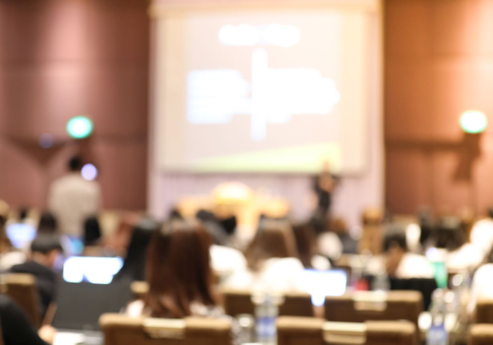 Abstract blurry background of employees seminar and De-focus teamwork staffs working meeting in conference room with projector screen.