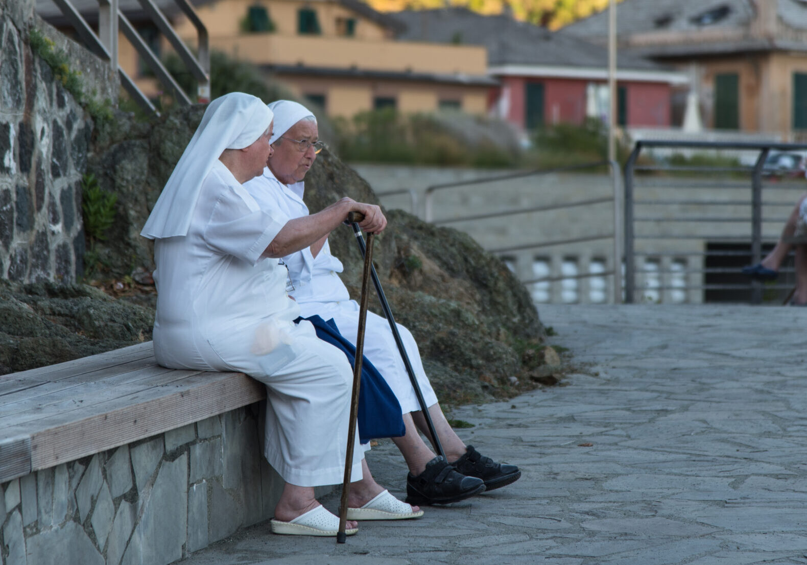 Bonassola, Liguria / Italy - August 24, 2016: two nuns sitting on a bench on the promenade by the sea, resting and enjoying the conversation in the early evening