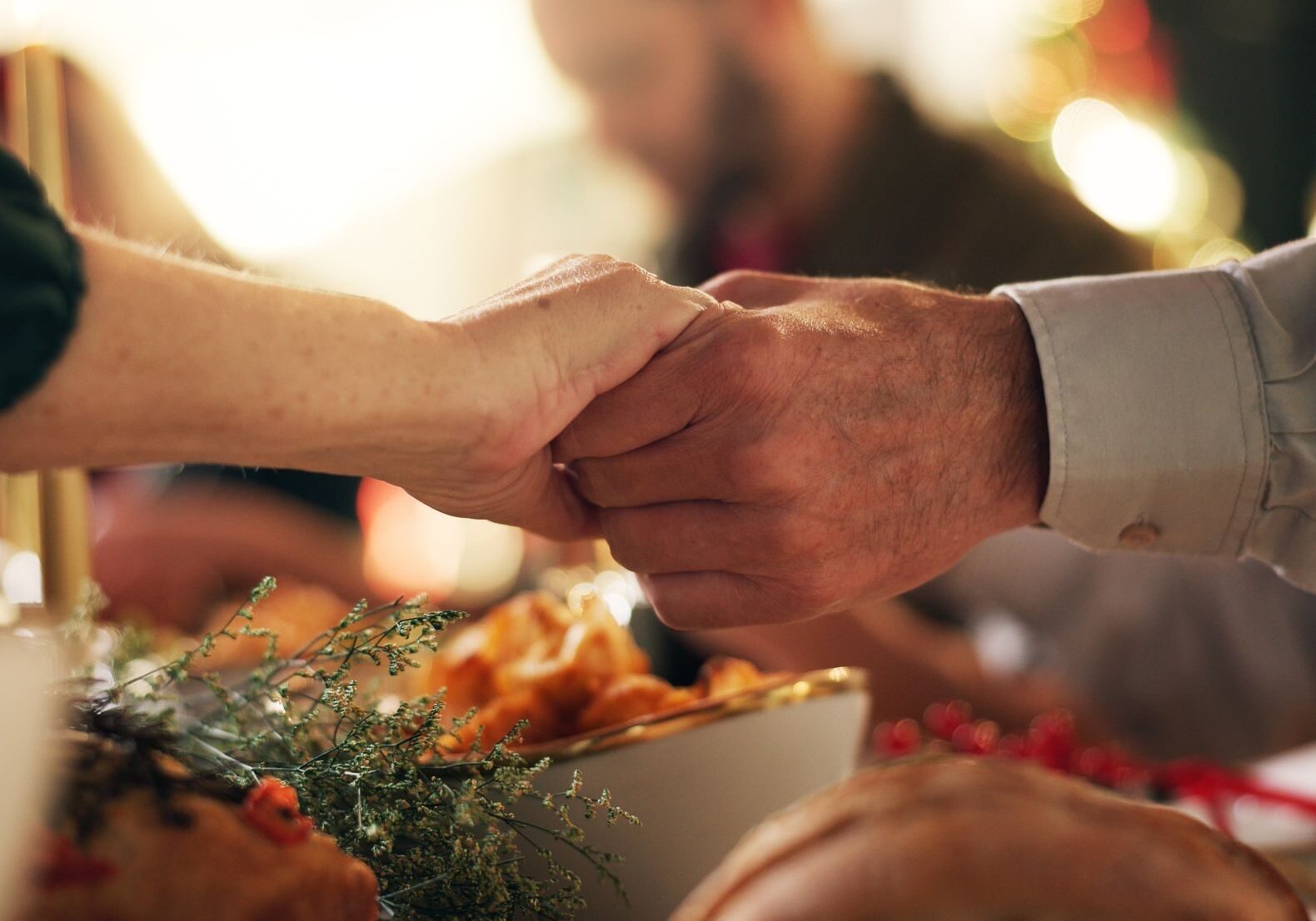 Holding hands, Christmas and prayer with family at dinner table for gratitude, holiday season and love. Worship, spiritual and support with closeup of people in home for festive celebration and trust